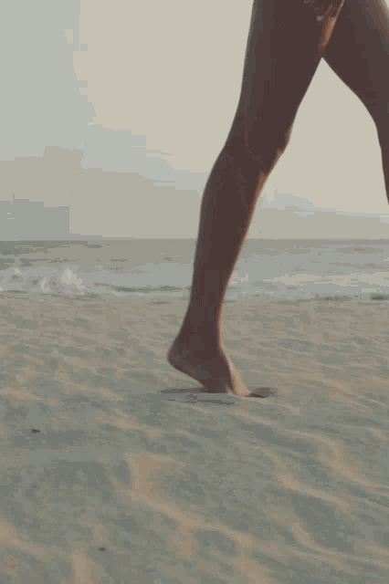 a woman is walking barefoot on the beach