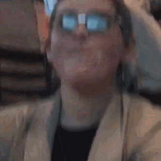 a woman wearing glasses is making a funny face while sitting at a table in a restaurant .