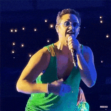 a man in a green tank top is singing into a microphone ..