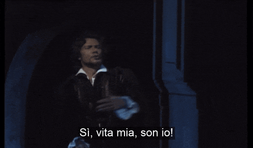 a man is singing in a dark room with the words si vita mia son io