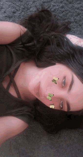 a girl with butterflies on her face is laying down