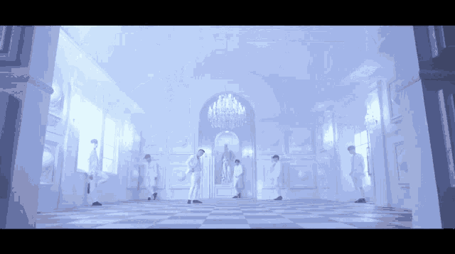 a group of men are standing in a room with a chandelier hanging from the ceiling