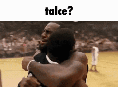 two men are hugging each other on a basketball court with the words talce written above them .