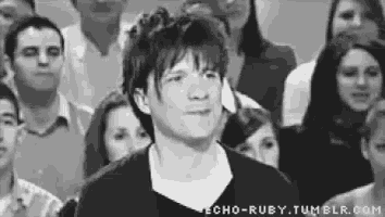 a man is standing in front of a crowd of people and making a face .