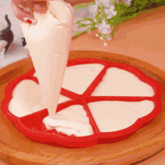 a person is pouring frosting into a heart shaped pan .