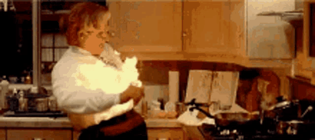 a woman is standing in a kitchen holding a flame in her hand .