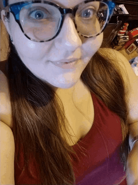 a woman wearing glasses and a red tank top smiles at the camera