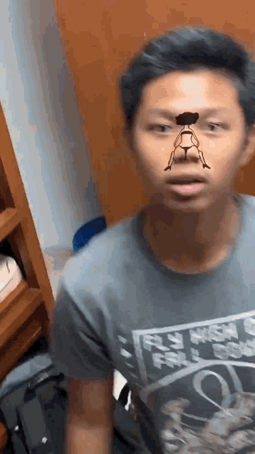a man wearing a gray shirt has a drawing of a woman on his nose