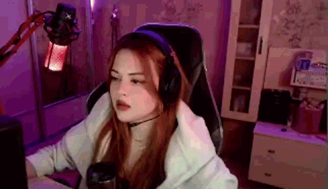 a woman wearing headphones and a microphone is sitting in front of a computer screen .