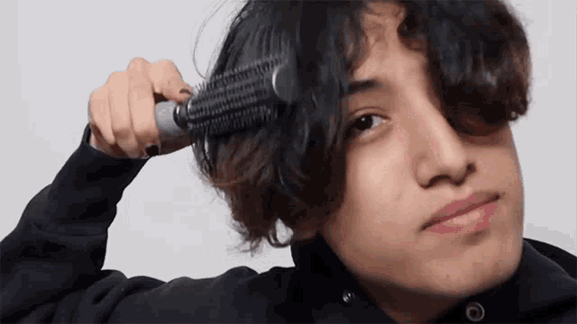 a young man is brushing his hair with a brush