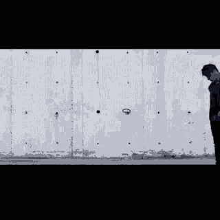 a man standing in front of a white wall looking down
