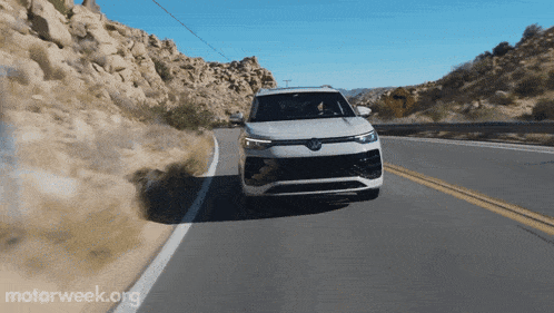 a white car is driving down a desert road with motorweek.org written on the bottom