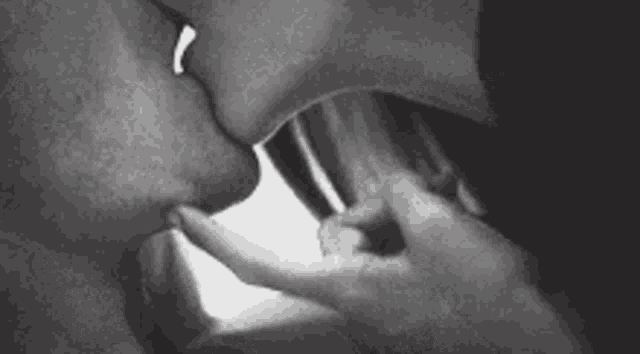 a black and white photo of a couple kissing .