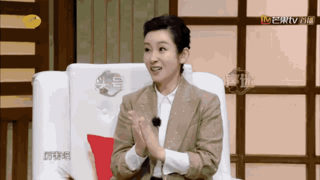 a woman sits in a chair with her hands together in front of a tv screen that says mtv