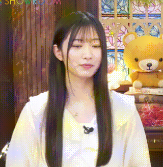 a young woman with long hair is standing in front of a teddy bear .