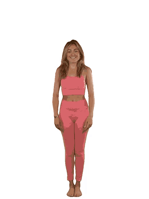 a woman in a pink top and pink leggings is standing with her arms in the air