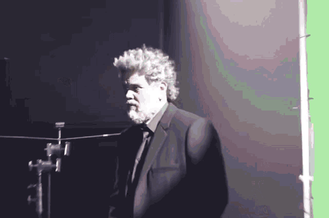 a man in a suit and tie standing in front of a green screen