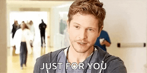 a man in a scrub top is standing in a hospital hallway and talking to someone .