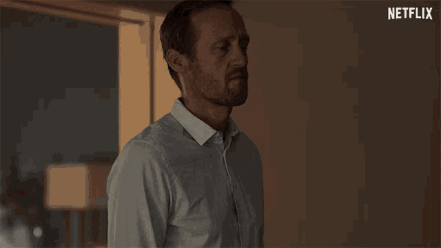 a man is standing in front of a window with a netflix logo in the corner