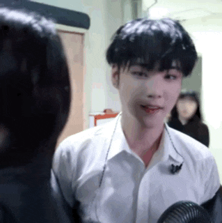 a man in a white shirt is talking to a woman in a hallway while holding a fan .