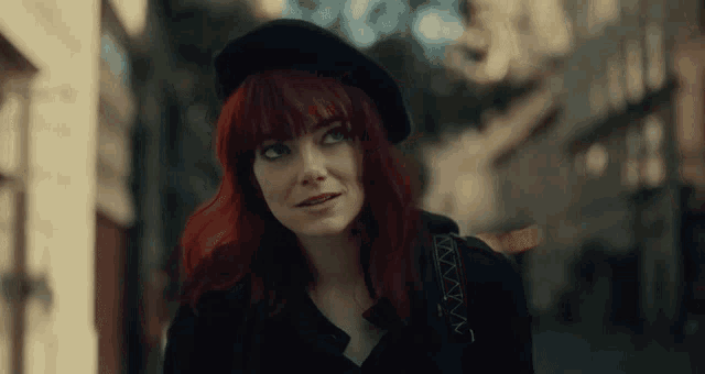 a woman with red hair is wearing a black beret and a black jacket