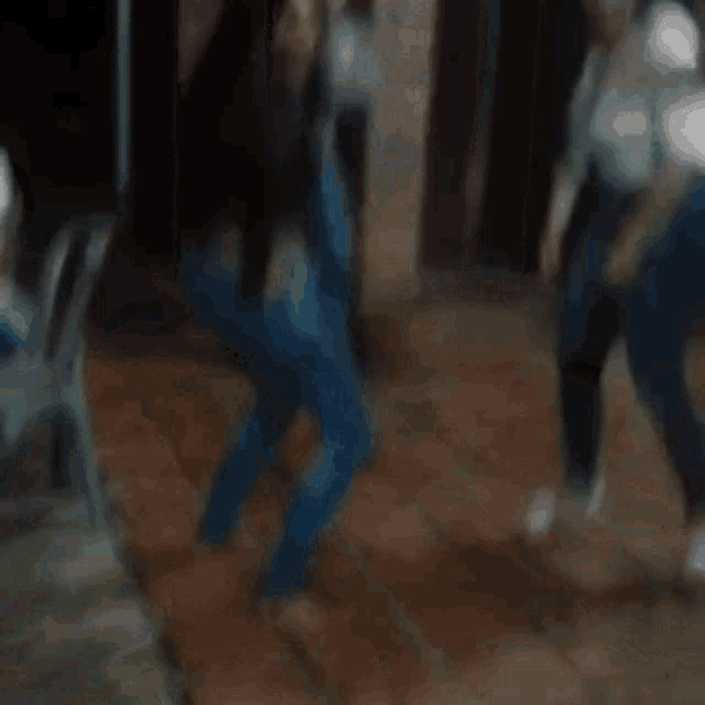 a woman in blue jeans is dancing in a dark room
