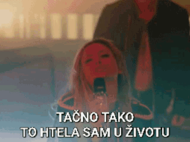 a woman is singing into a microphone while a man stands behind her