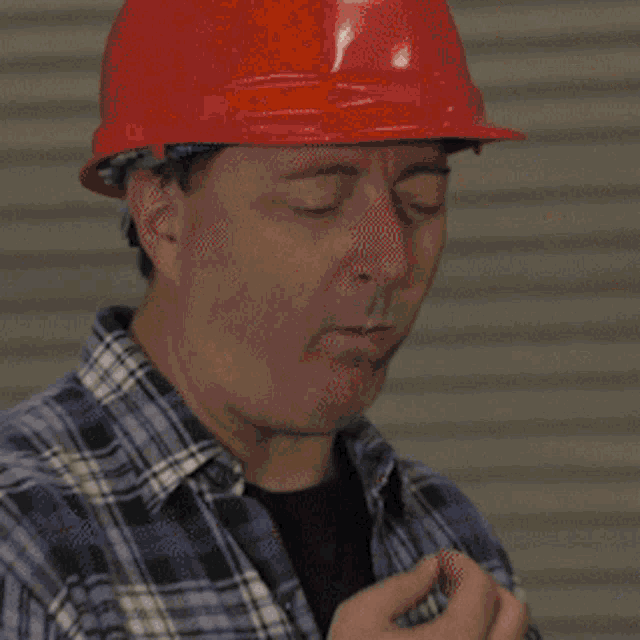 a man in a plaid shirt is kneeling on the floor working on a microphone