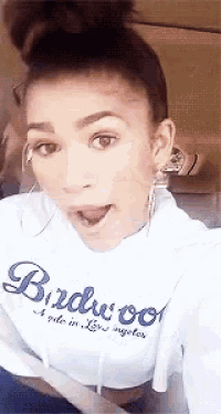 a woman is taking a selfie with her tongue out while wearing a birdwood sweatshirt .
