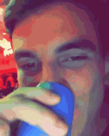 a close up of a man 's face drinking from a blue mug