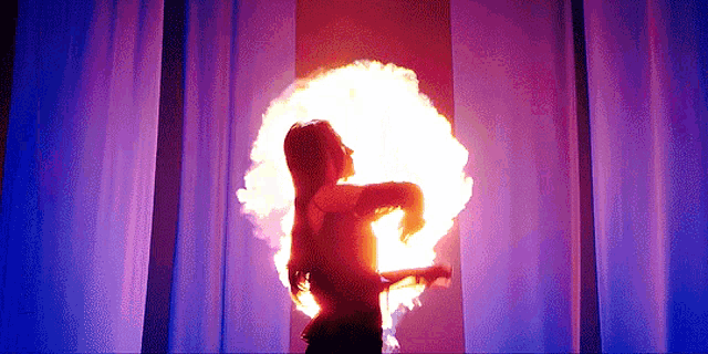 a woman is standing in front of a large circle of fire