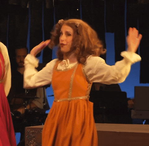 a woman in an orange dress and white shirt is dancing