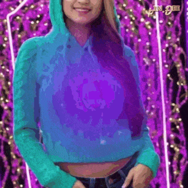 a woman wearing a blue sweater with a purple background