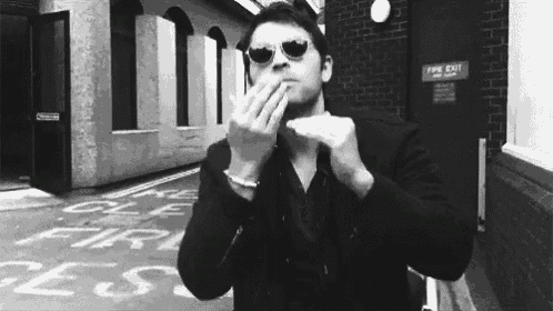 a man wearing sunglasses is blowing a kiss while smoking a cigarette .