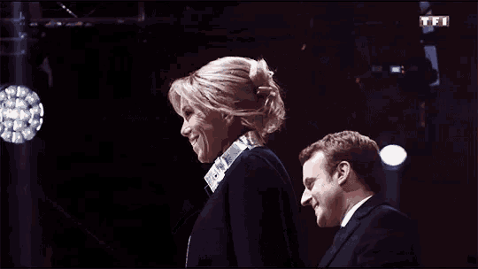 a man and a woman are standing next to each other with a tfi logo behind them