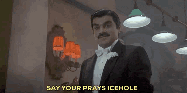 a man in a tuxedo and bow tie is saying " say your prays icehole "