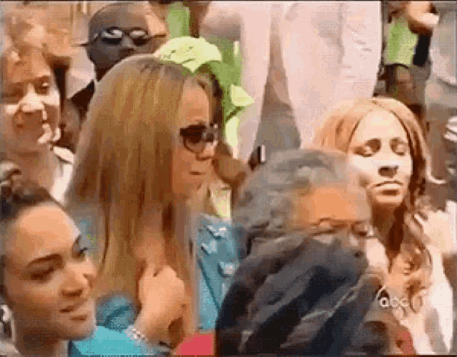 a group of people are sitting in a crowd and one woman is looking at another woman .