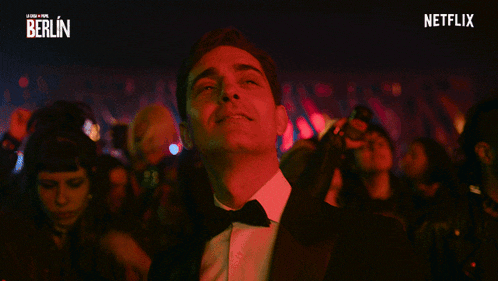 a man in a tuxedo is smiling in front of a netflix banner