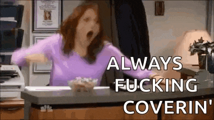 a woman in a purple shirt is yawning while sitting at a desk with a bowl of popcorn .
