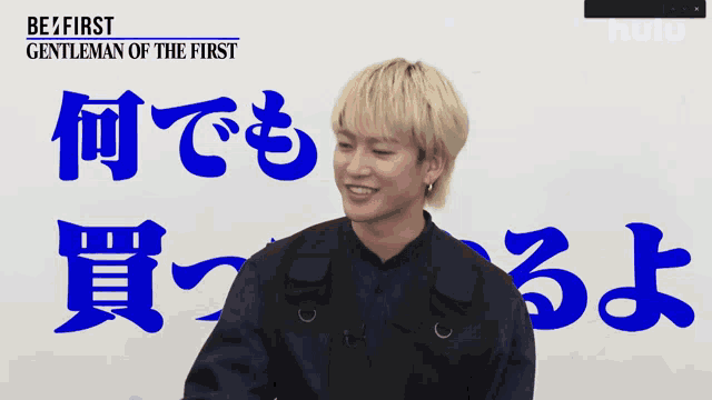 a man is smiling in front of a sign that says gentleman of the first