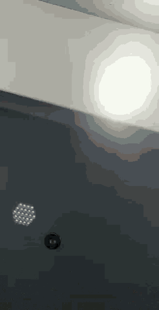 a ceiling light is shining on a dark wall .