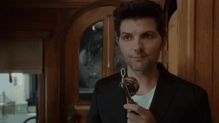 a man in a suit and white shirt is holding a key in his hand .