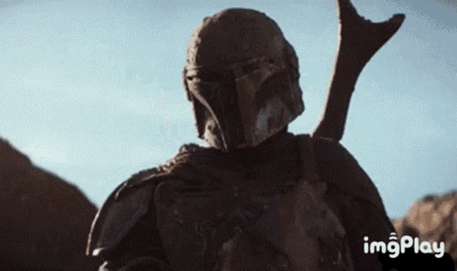 a close up of a person wearing a helmet and holding a gun in the desert .