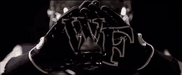 a close up of a person wearing a pair of black gloves with the letters wvf on them