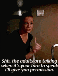 a woman is sitting at a table with her finger on her lips and a caption that says shh , the adults are talking