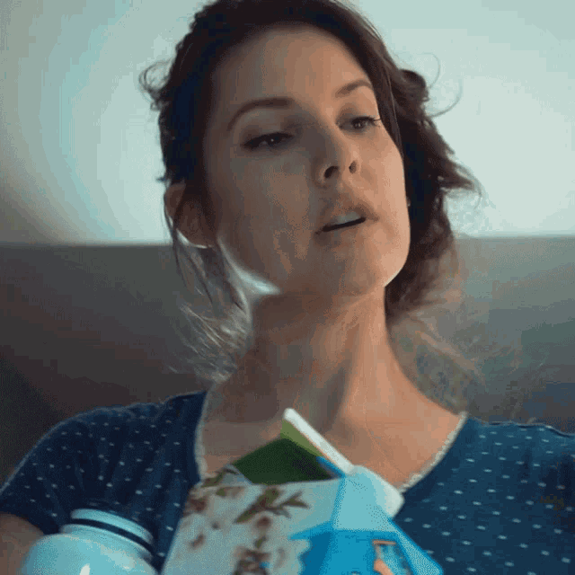 a woman in a blue shirt is holding a milk carton