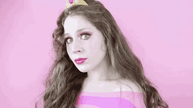 a woman is wearing a tiara and a pink dress .