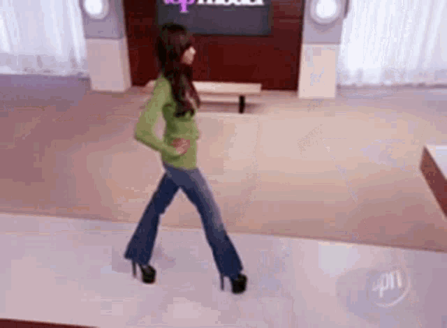 a woman in a green sweater and blue jeans is walking on a runway .