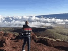 a man standing on top of a mountain looking out over a cloudy valley