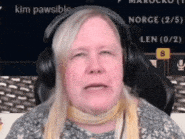 a woman wearing headphones is sitting in front of a screen that says " kim pawsible "